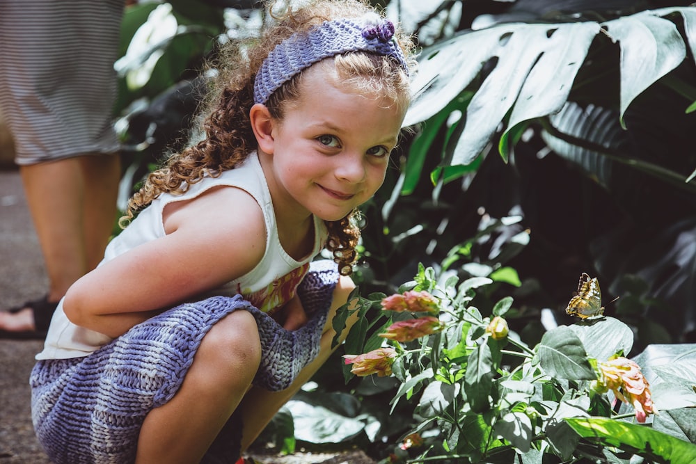 menina tirando selfie perto de flores vermelhas