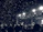 A candid shot of a teen crowd jumping and cheering at a nighttime outdoor concert.