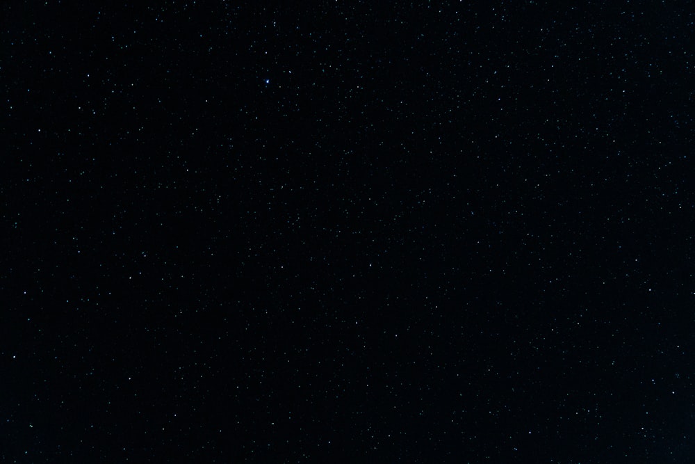 a night sky with stars and a plane in the foreground