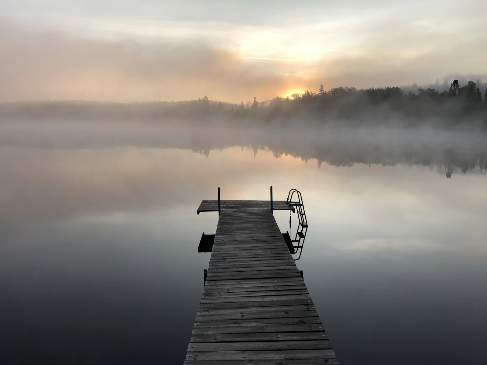 A dock on a still lake at dawn