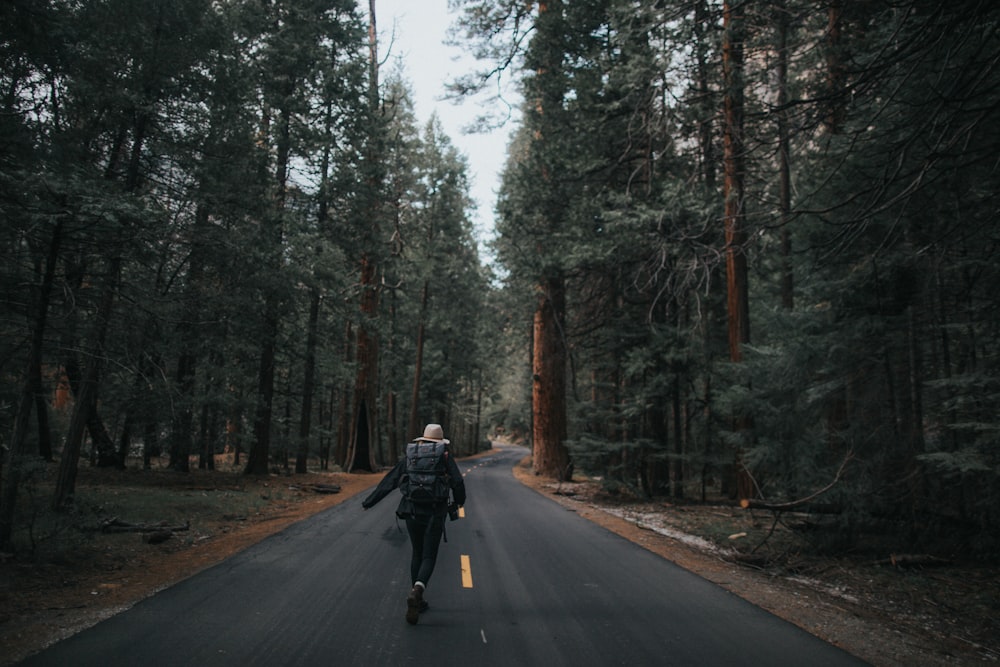 person standing on road between trees