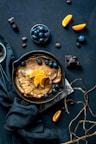 pancake with orange and blueberries beside scattered chocolate and coffee beans