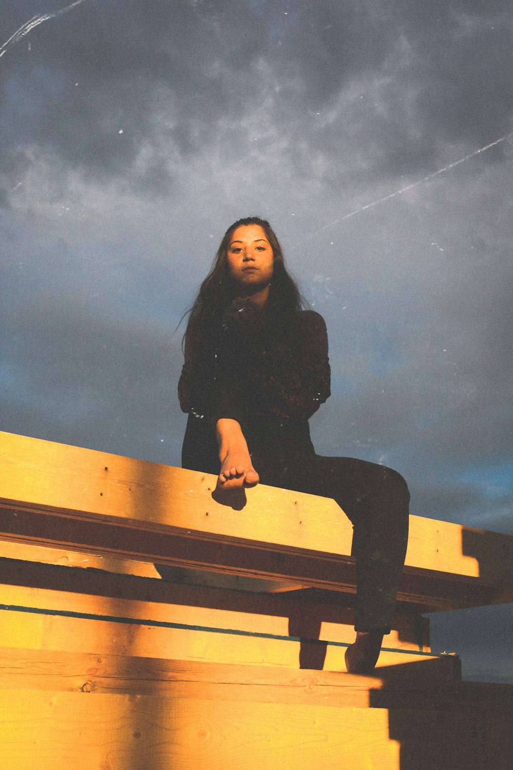 woman sitting on bench under gray clouds