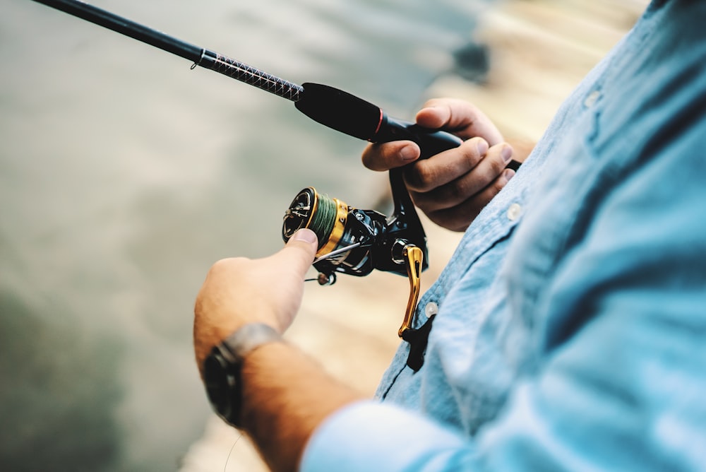 person holding black and yellow fishing reel