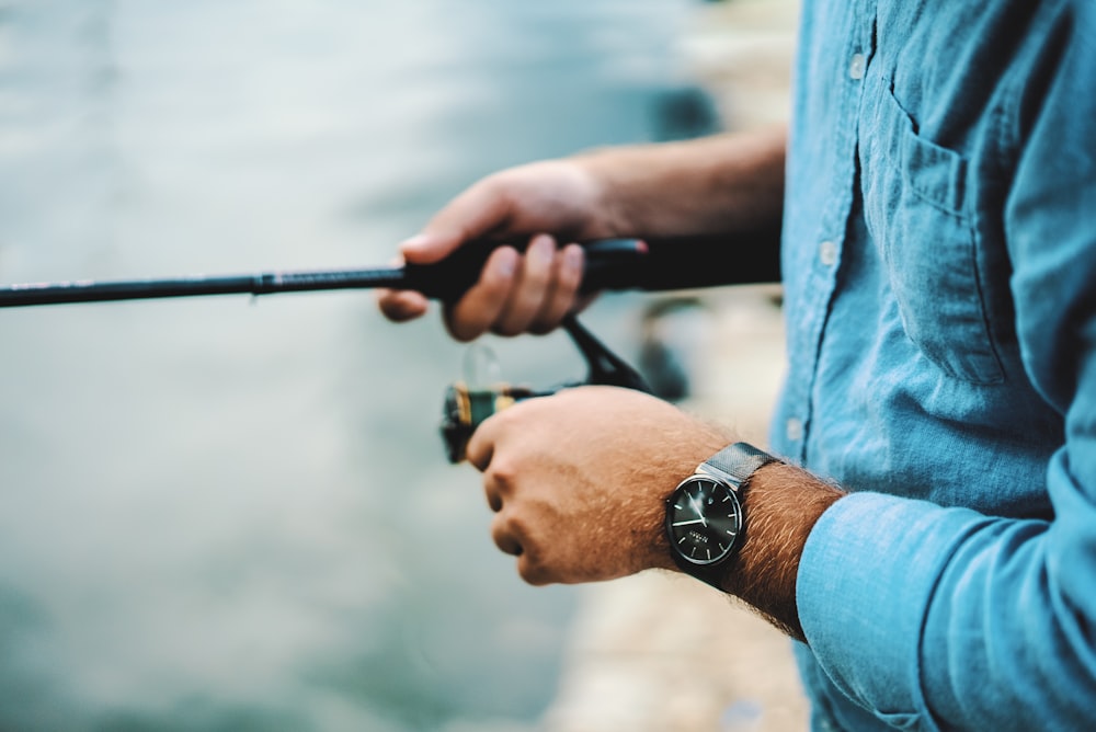man wearing blue dress shirt holding fishing rod