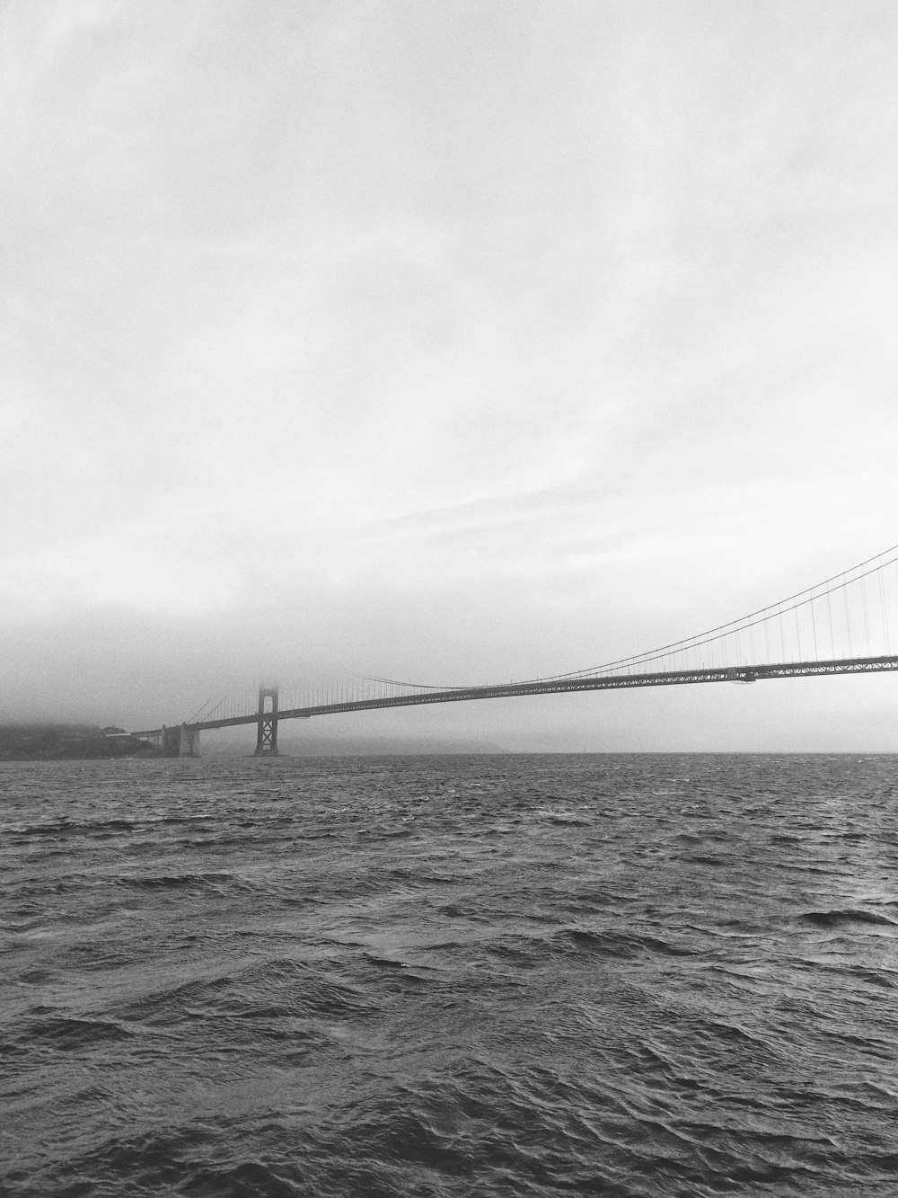 Foto en escala de grises de un puente cerca del cuerpo de agua