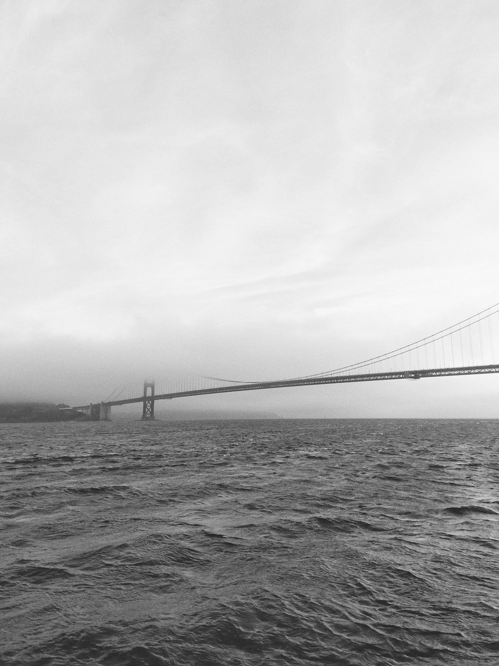 grayscale photo of bridge near body of water
