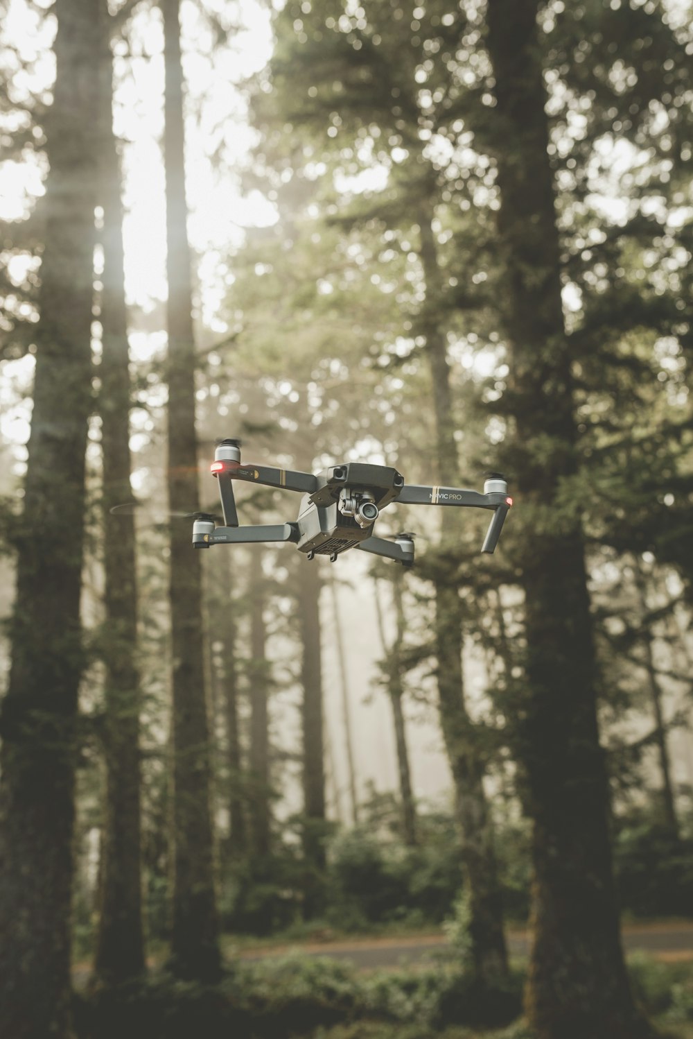 drone quadricottero DJI Mavic Pro grigio e nero nell'aria medio-alta vicino alla foresta durante il giorno