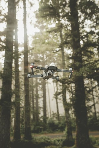 An aerial view of a drone flying above rooftops and tree-lined streets in daylight