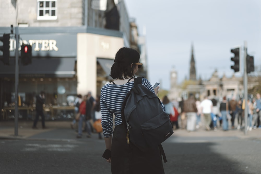 woman wearing striped shirt holding phone on side of street