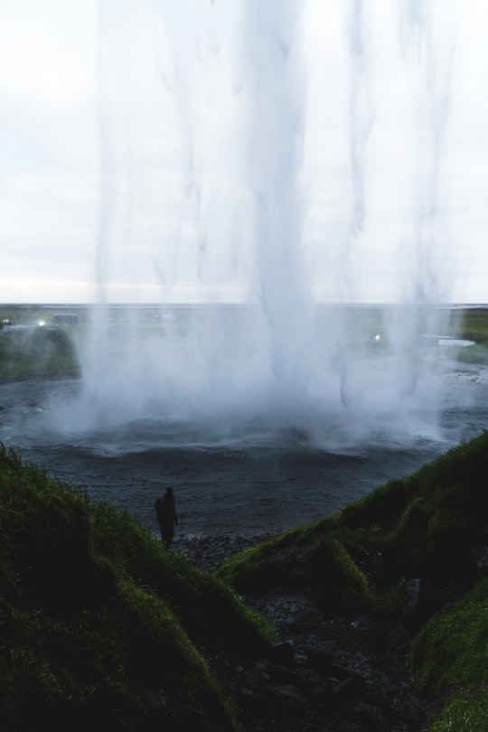 person standing near body of water in Seljalandsfoss Iceland
