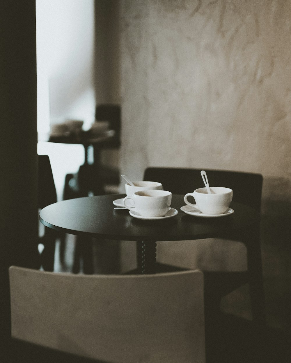 Drei Teetassen aus weißer Keramik auf schwarzem Holztisch