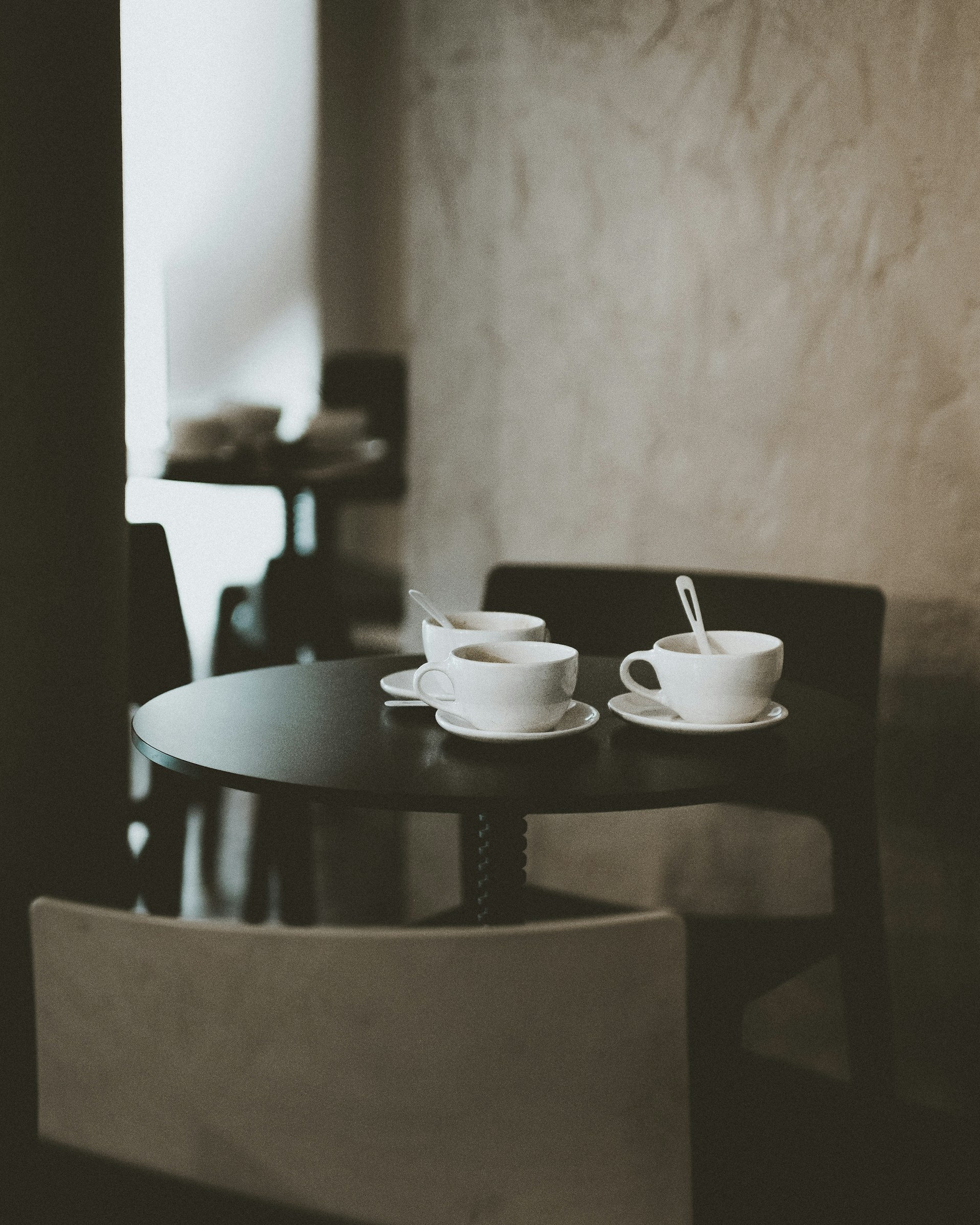 three white ceramic teacups on black wooden table