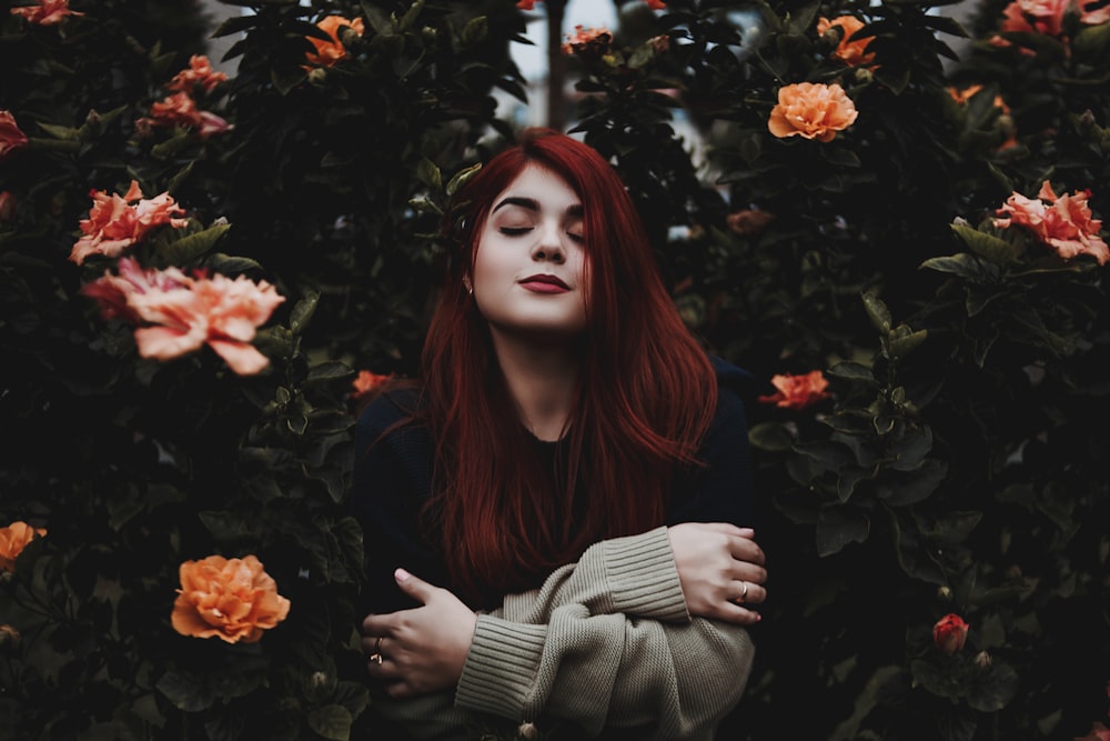 woman surrounded by green and yellow petaled flower hugging herself at daytime