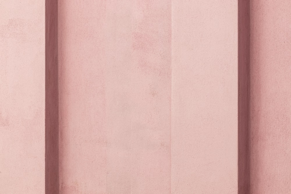 eine rosafarbene Wand mit vertikalen Linien darauf