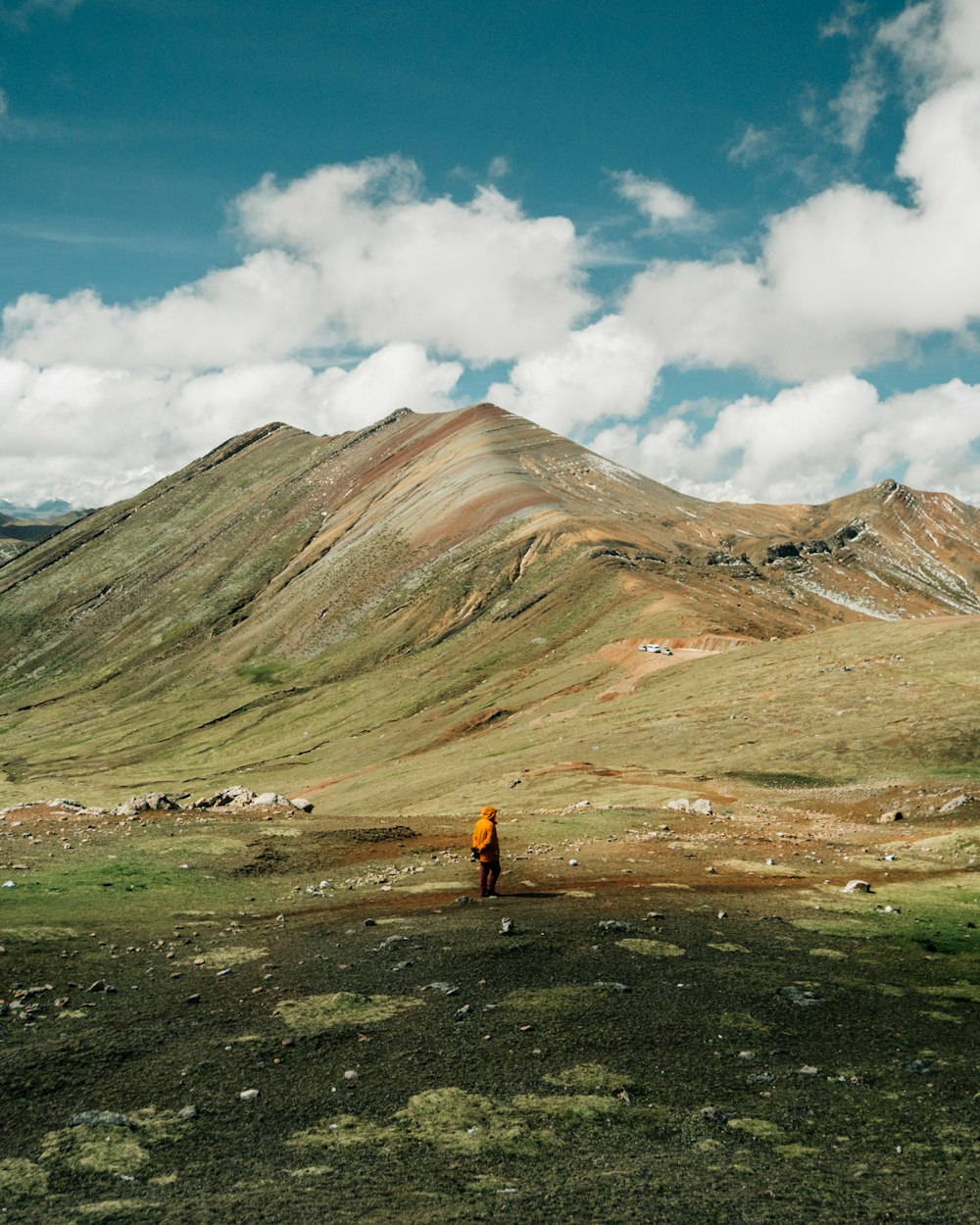 hombre de pie en el campo de hierba verde cerca de la cresta de la montaña