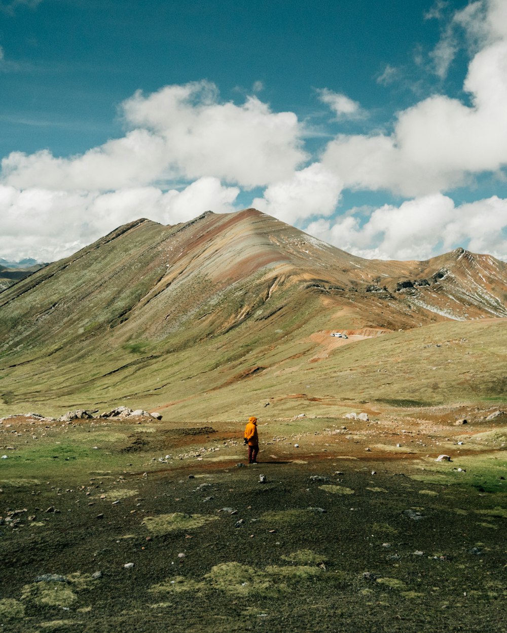 man standing on green grass field near mountain ridge