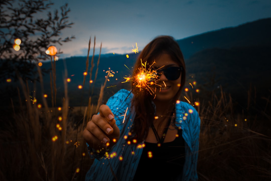 woman holding sparkling stick in field