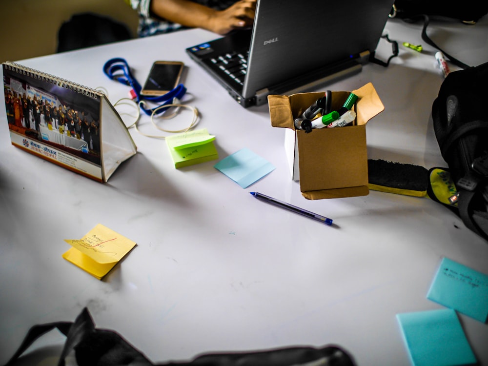 Persona che si siede davanti al computer portatile grigio con post-it colorati assortiti sul tavolo