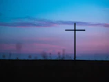 A peaceful outdoor scene with a cross silhouetted against the sky.