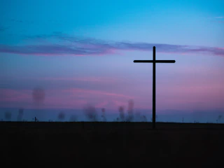 A serene twilight sky with a faint silhouette of a UFO and a glowing cross in the distance.