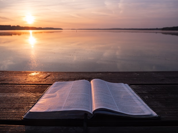 Bible on top of table and body of water