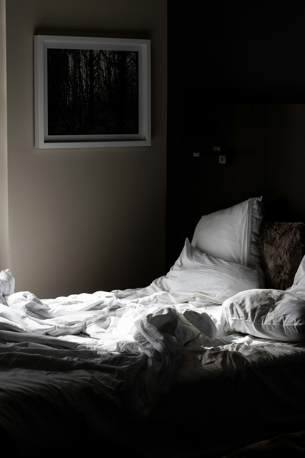 흰색 침대보와 베개 위에 정사각형 흰색 사진 프레임