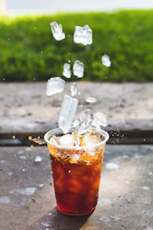 macro photography of dropping ice cube in cup
