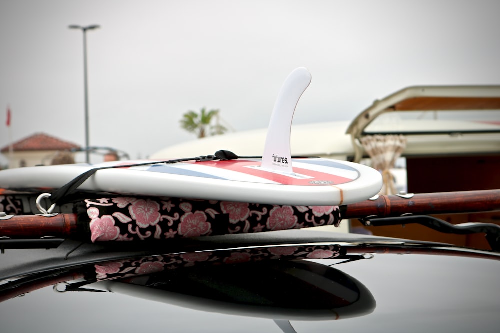 Planche de surf blanche, rouge et bleue sur photographie en gros plan de voiture noire