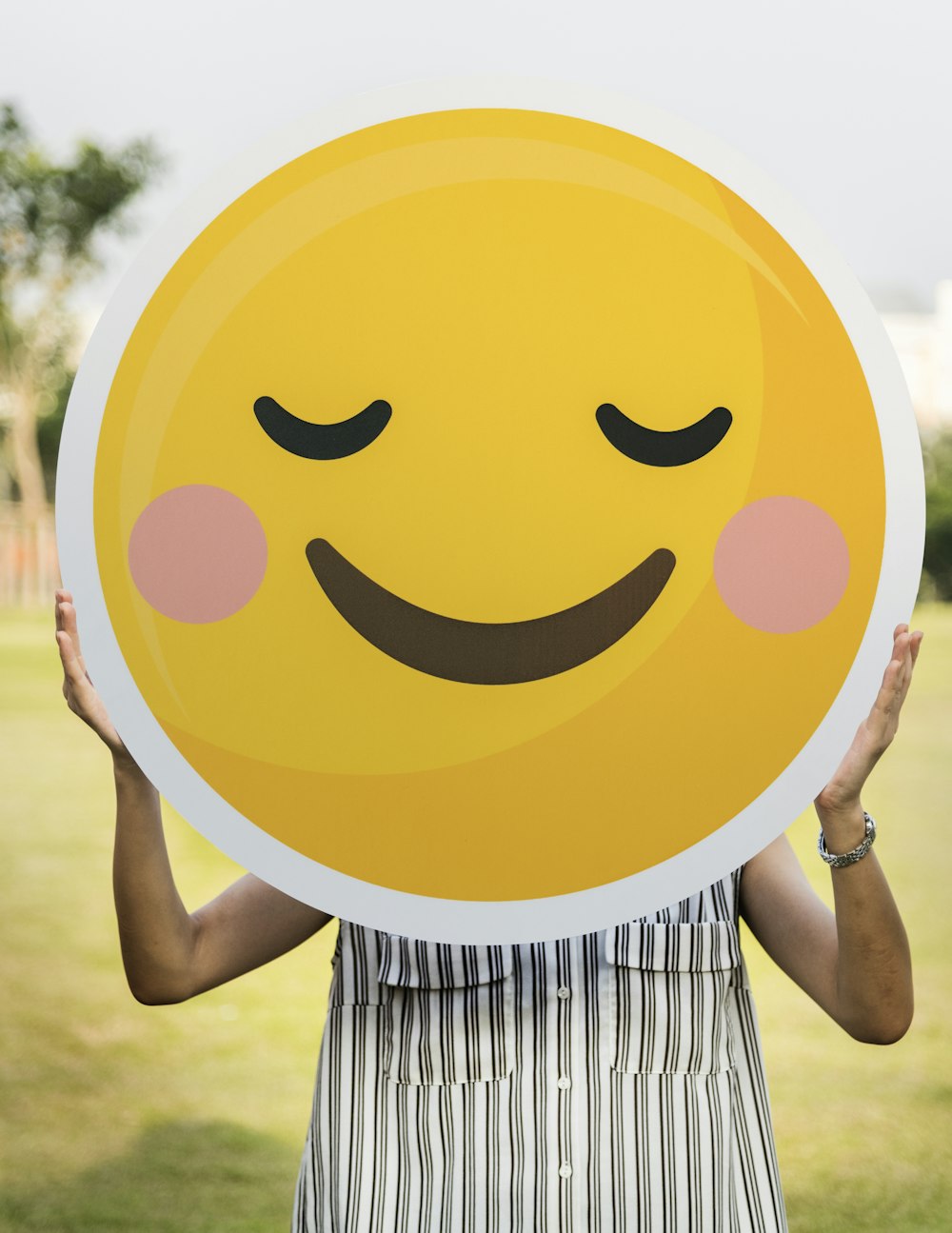 woman holding blush emoticon during daytime