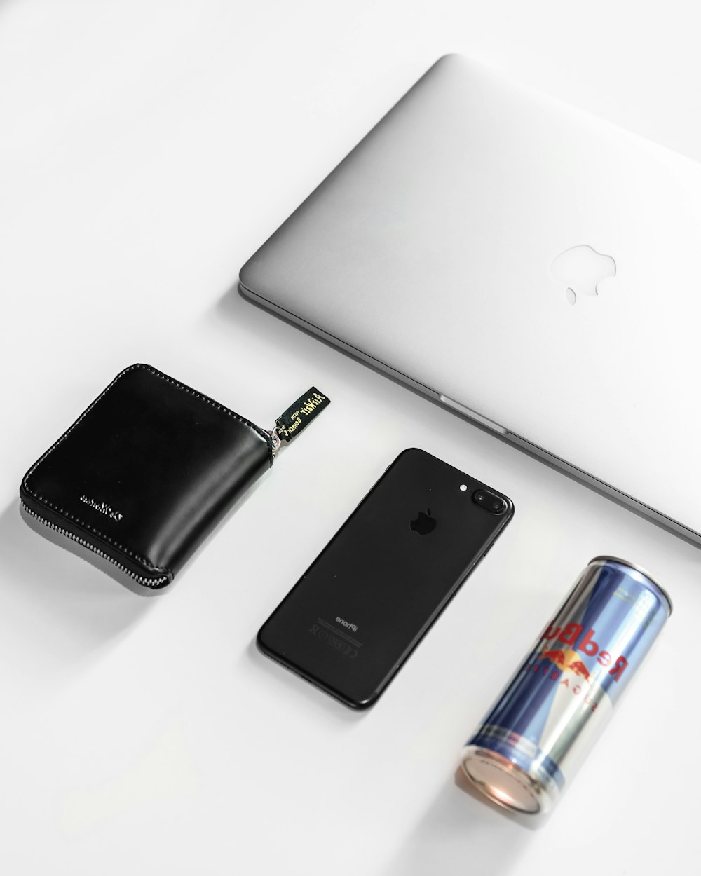 a white table with a laptop, cell phone, wallet and lighter