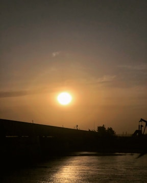 Sunset over a bustling oil field with active machinery.