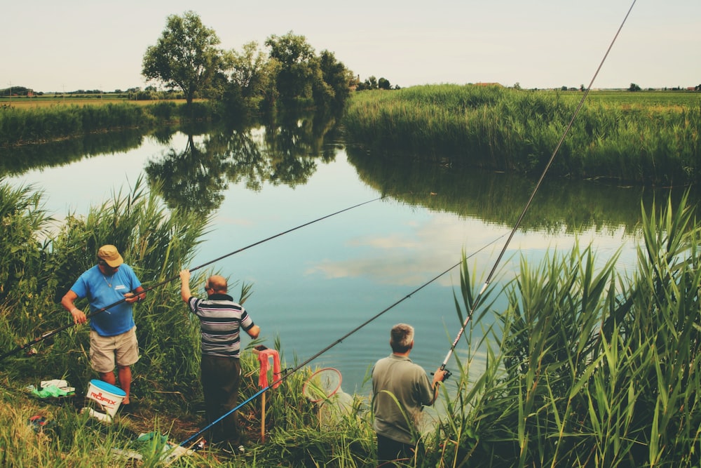 three men fishing during day