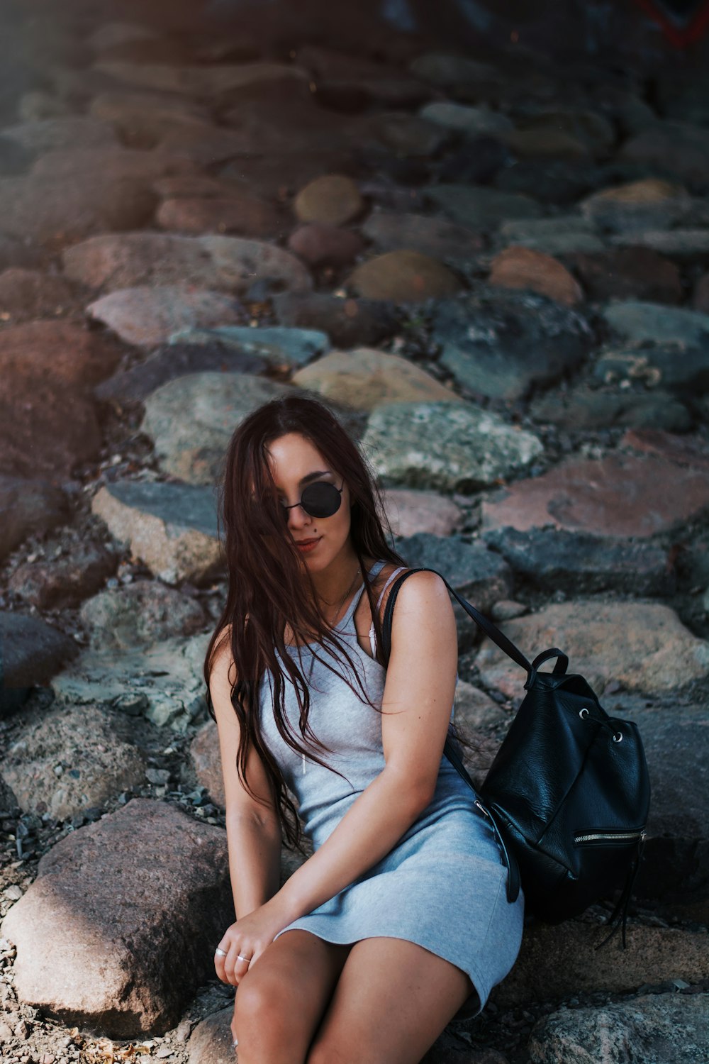 woman in gray mini dress sitting on rocks during daytime