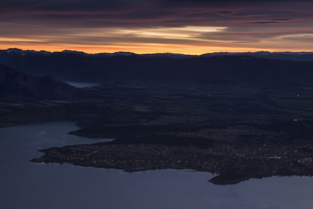 an aerial view of a lake and mountains at sunset