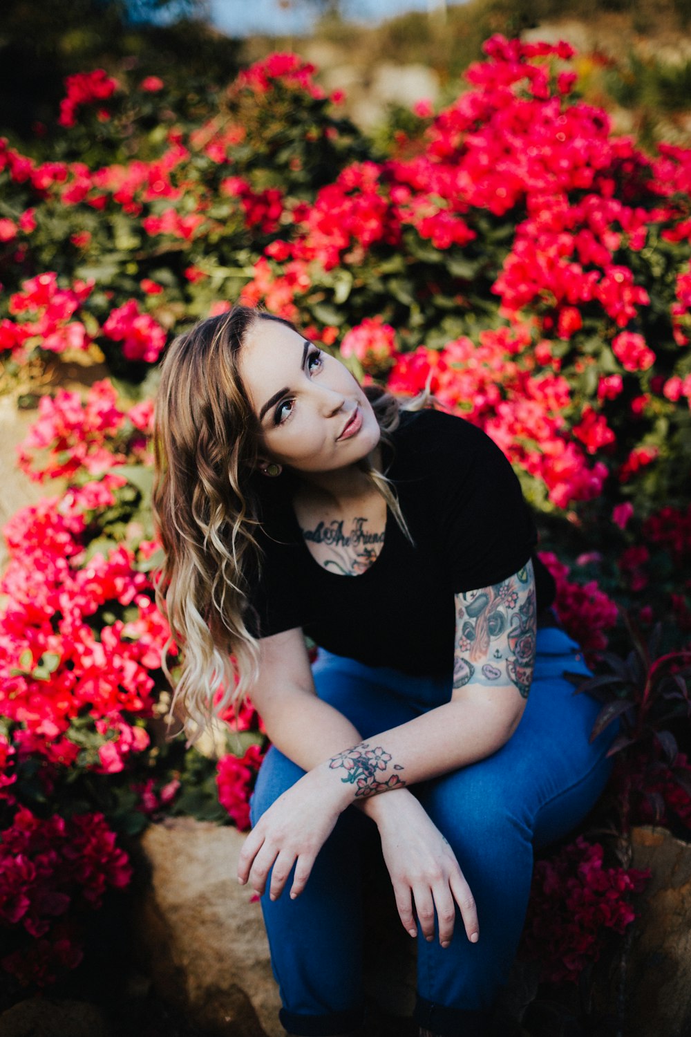 woman sitting beside red bougainvillea flower