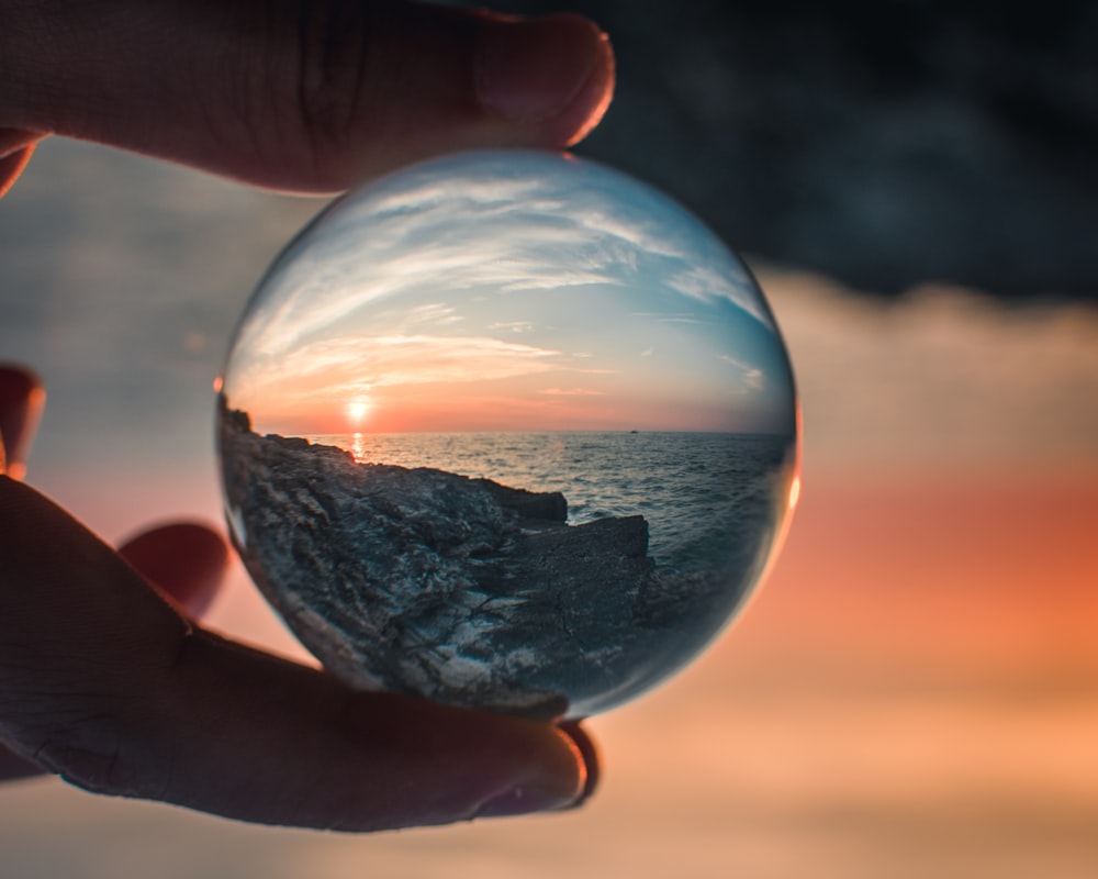 Persona sosteniendo una foto redonda de bola de vidrio transparente