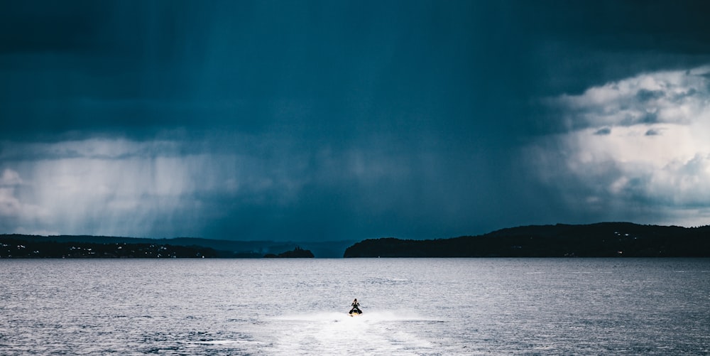 person riding watercraft at the middle of the sea