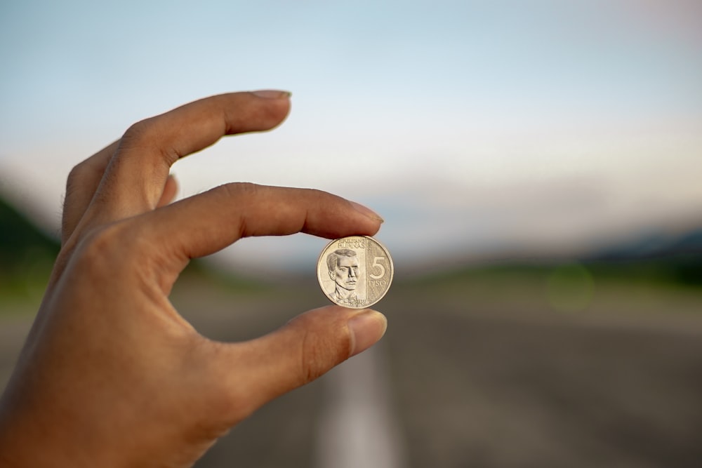 selective focus photography of person holding coin