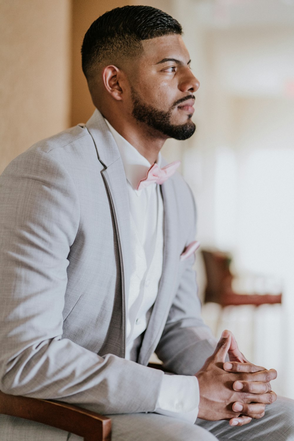 man wearing gray and white tuxedo while sitting on chair