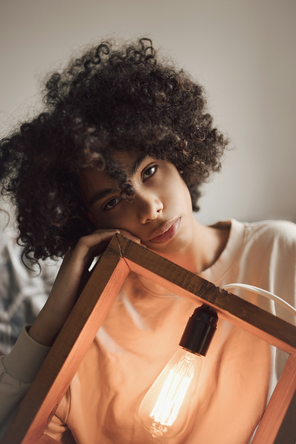 woman holding brown wooden framed light bulb