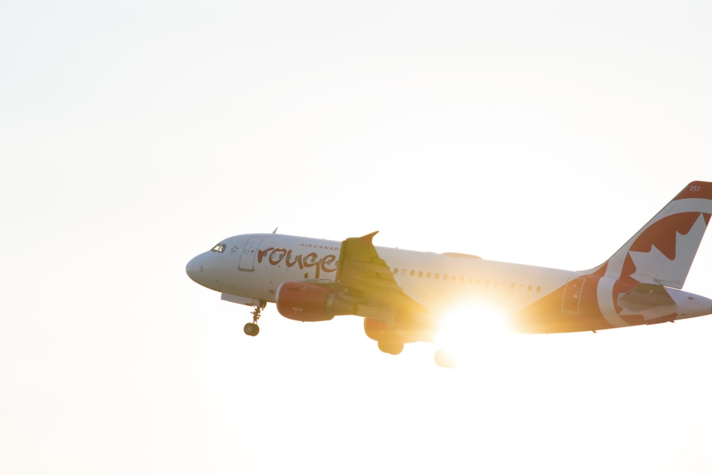 Avión blanco y naranja en el aire durante el día