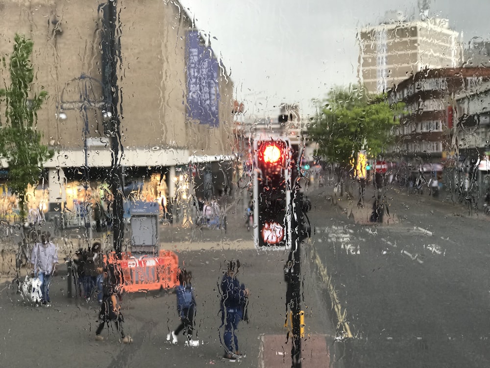 people standing beside road with stop traffic light signage