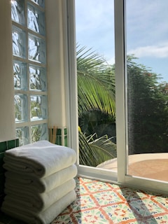 Soft white towels rolled and stacked beside a small indoor palm plant.