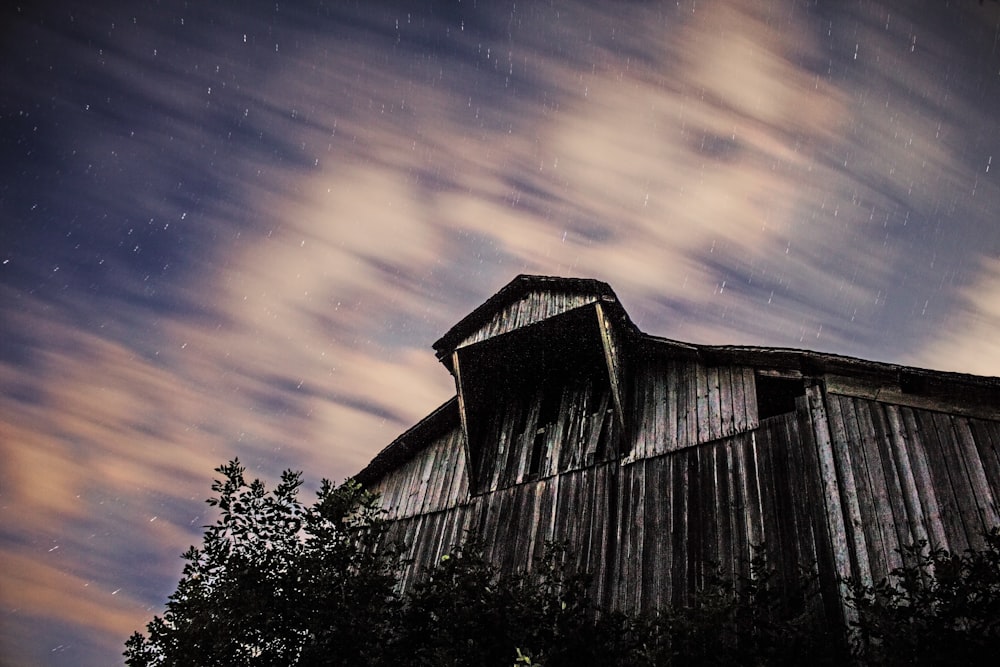 low-angle photography of wooden barn under cloudy sky