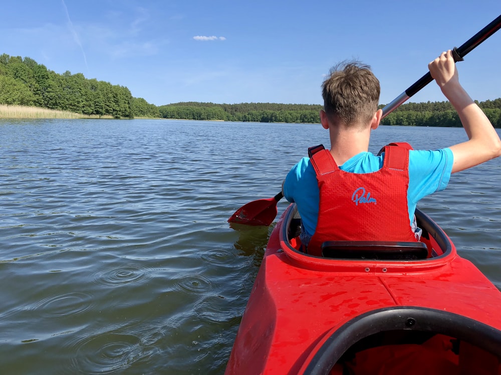 man paddling while riding kayak