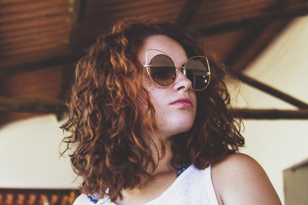 woman wearing gray framed oversized sunglasses and white tank top