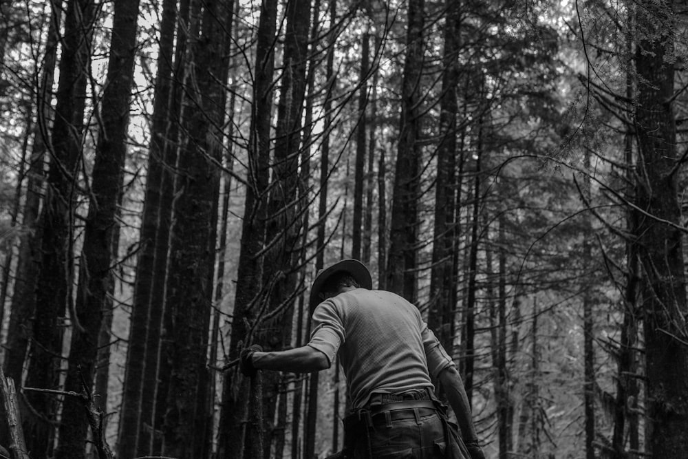 man standing in forest grayscale photography
