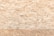 A textured surface composed of wood chips and strands oriented randomly and pressed together. The material appears natural and rustic, with variations in the shades of brown, beige, and tan.
