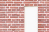 A red brick wall with an inset rectangular section filled with plain white plaster. The bricks are neatly arranged in a classic pattern with visible mortar lines.